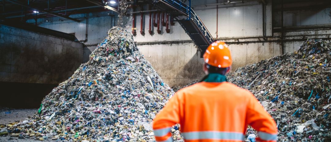 Sanitation worker looking at mountains of sorted rubbish